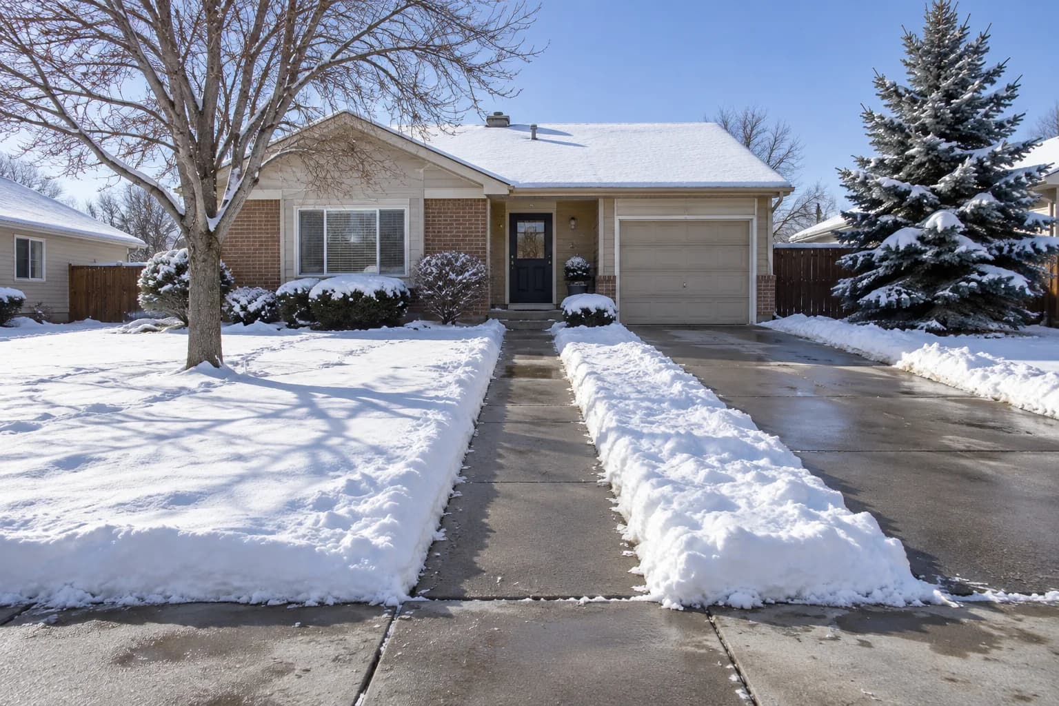 A cleared walkway and driveway in front of a snowy house